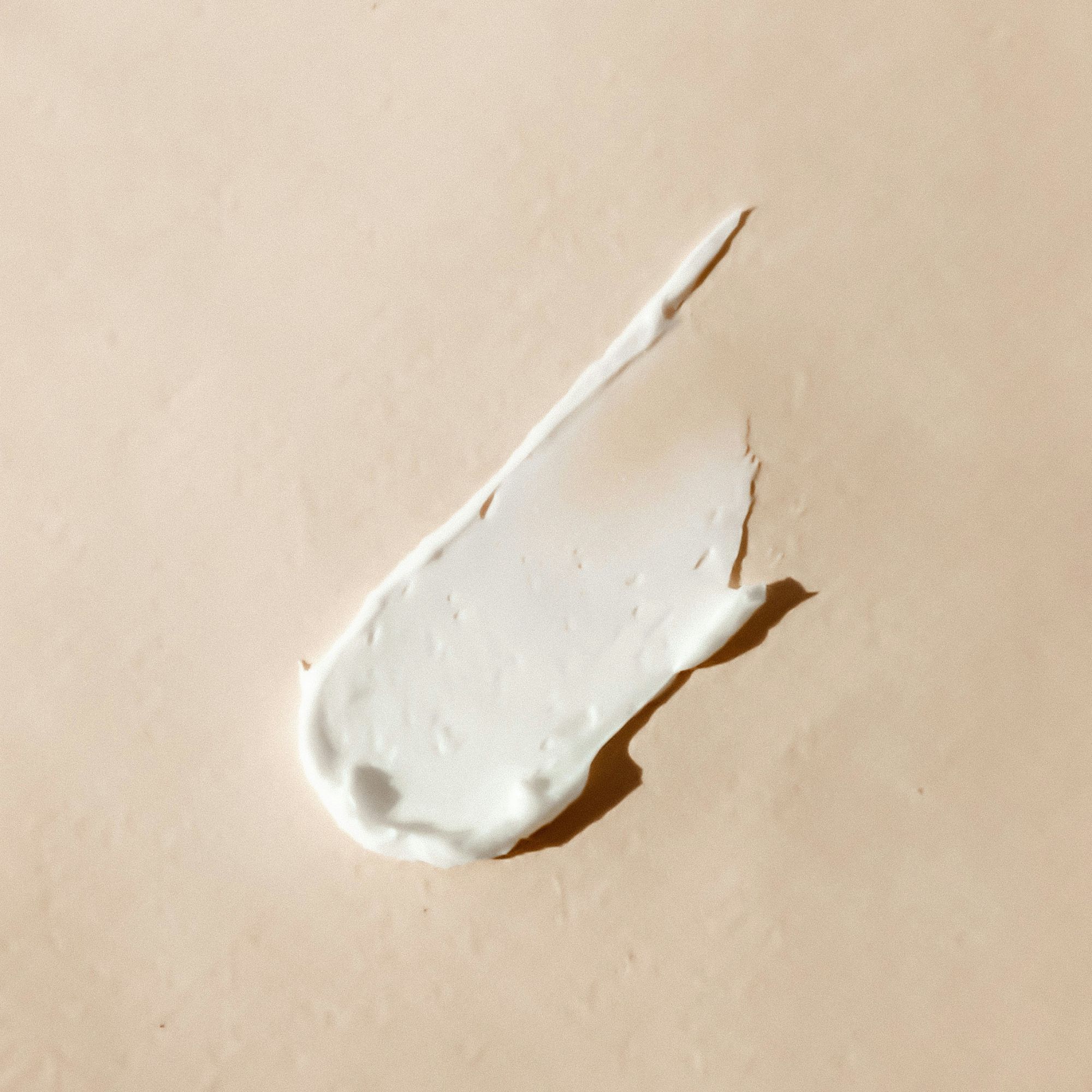 Close-up of a pea-sized amount of cream on skin-toned background